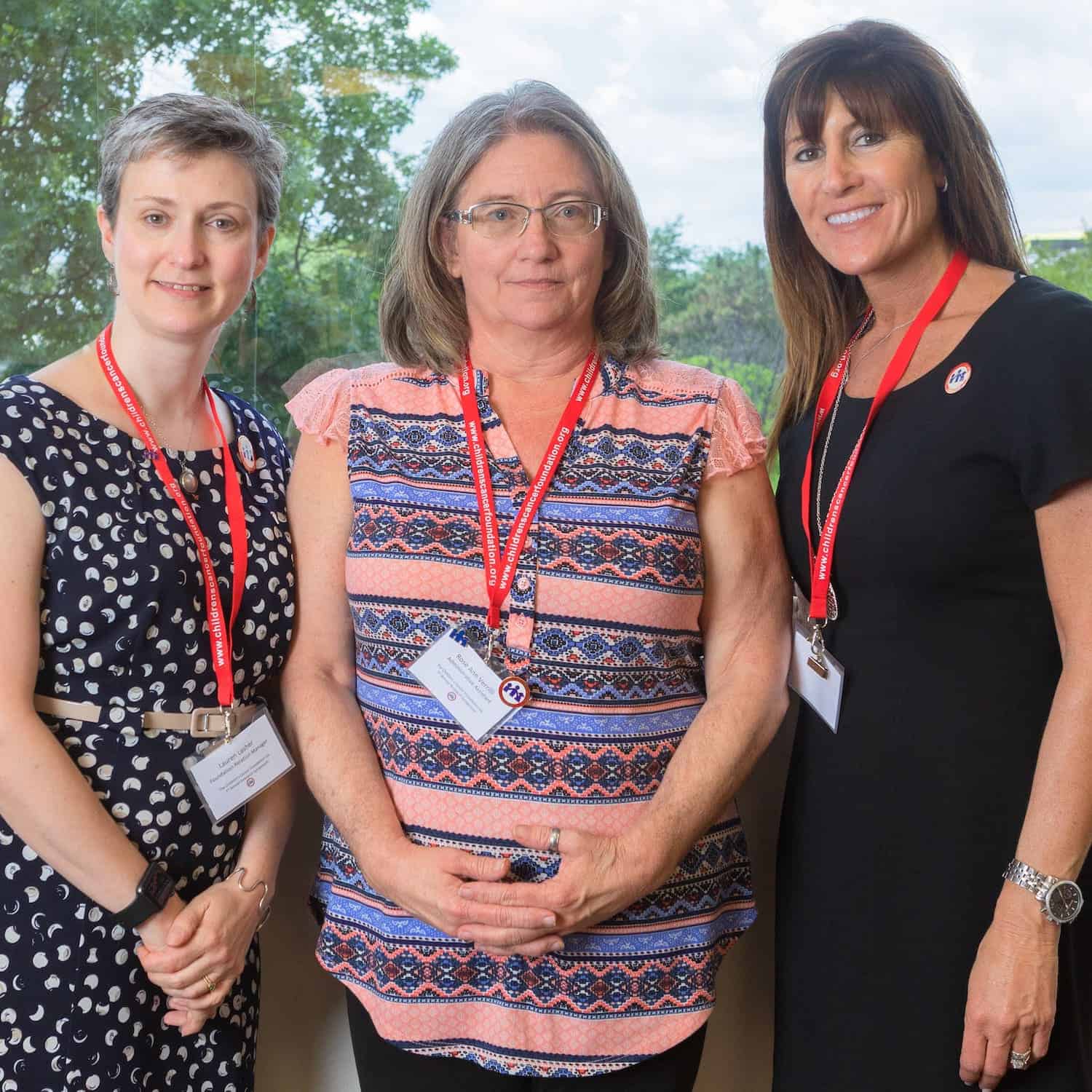 Three women standing outdoors wearing conference badges.