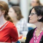 Two women attentively listening at a conference or seminar.