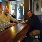 Two men enjoying drinks and conversation at a bar counter.