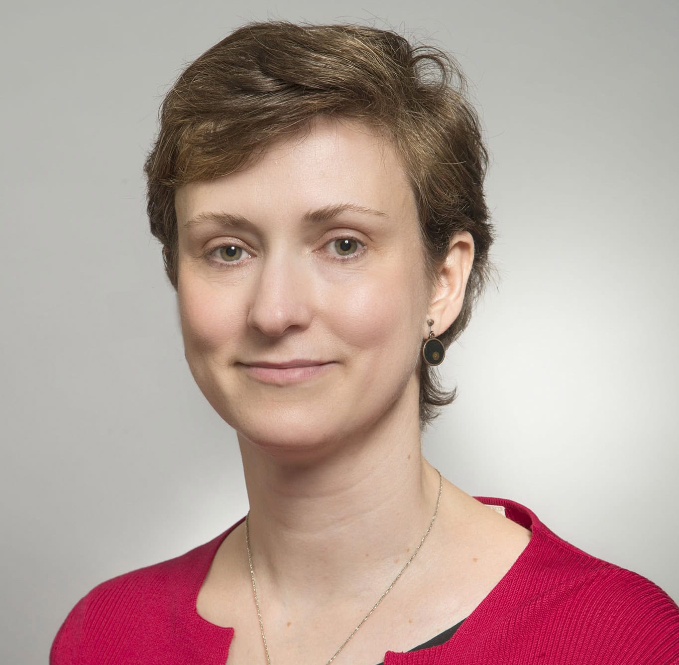 Professional portrait of a woman with short hair wearing a red top.