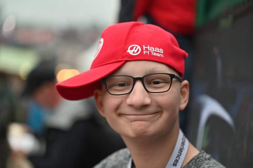 A smiling person wearing glasses and a red cap tilted to the side.